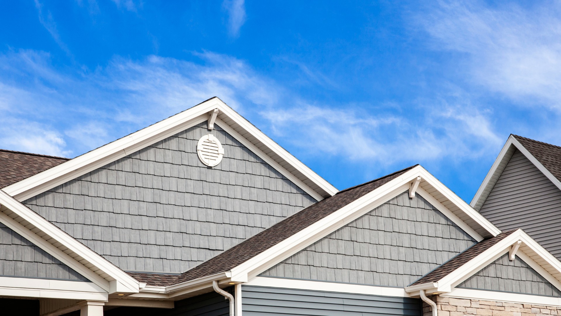 Hero image for CT Deck & Gutter image of top of a home with multiple gables and peaks, with a blue sky background