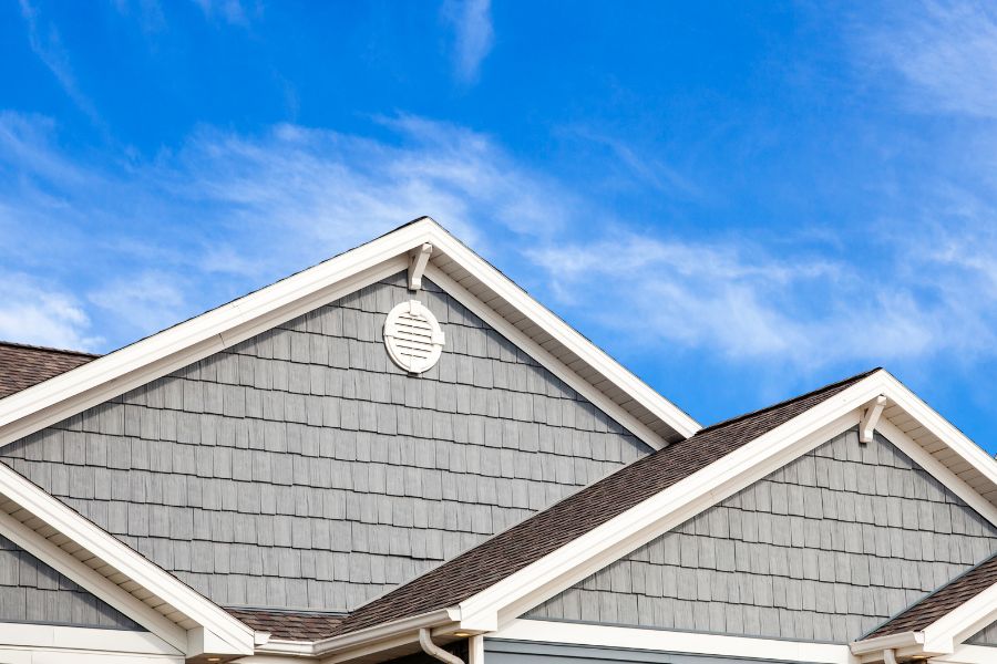 Image of roof area of a gray-sided house with blue sky